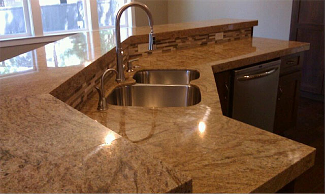 Granite kitchen counter with raised stone bar and undermount sink